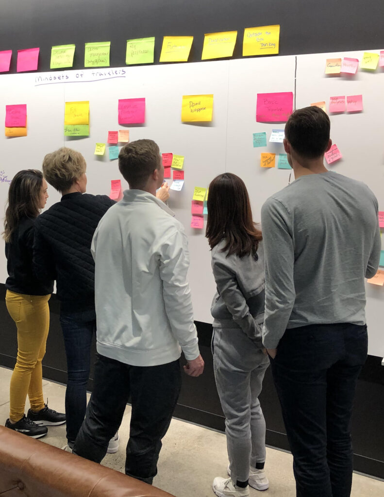 Group of people looking at sticky notes on white board